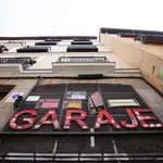 Imagen de la entrada de un garaje privado en Madrid, en el que cuelga la para en rojo "Garaje", y en el que se encuentran numerosos carteles de se vende y se alquila plaza de garaje para coche o moto.