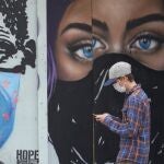 Un joven con mascarilla pasea frente a un grafiti en Austin, Texas