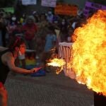 A fire breather burns a poster with the word "Patriarchy" during a march commemorating Women's International Day in Asuncion, Paraguay, Monday, March 8, 2021. (AP Photo/Jorge Saenz)