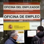 Dos hombres miran el cristal de una oficina de empleo