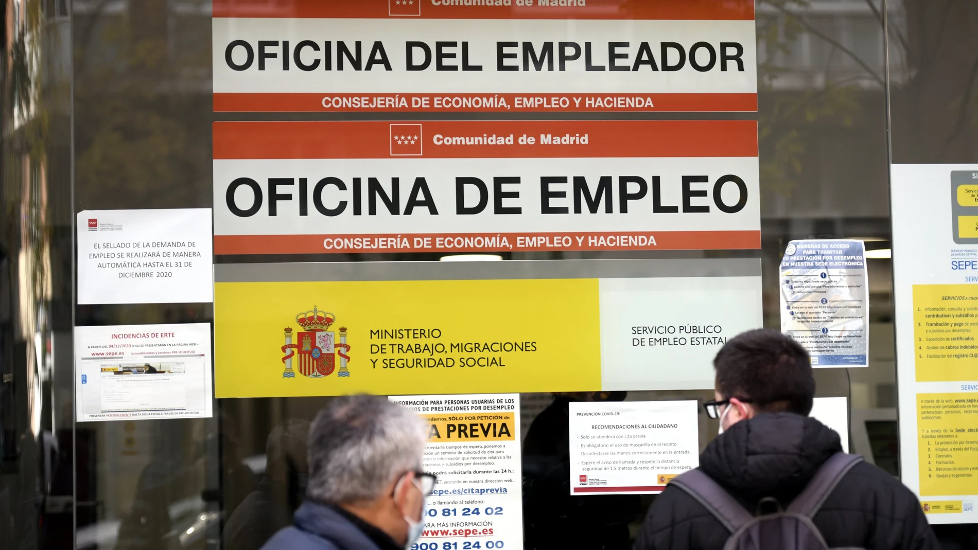 Dos hombres miran el cristal de una oficina de empleo