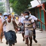 Un hombre que recibió un disparo durante una ofensiva contra manifestantes antigolpistas muestra un saludo de tres dedos mientras lo ayudan en Thingangyun, Yangon