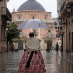Una fallera se dirige a la basílica de la Virgen de los Desamparados de València para realizar una ofrenda floral
