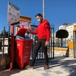 Un hombre echa una mascarilla dentro de un contenedor de color rojo que tiene como único fin recoger las mascarillas y guantes en Gilena (Sevilla).EFE/Fermín Cabanillas