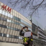 Un oficial de seguridad sostiene un cartel que dice "No se permiten fotos para uso comercial" frente a una tienda H&M en una zona comercial de Sanlitun en Pekín