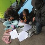 Un solicitante de asilo ayuda a sus hijos a hacer sus deberes en un campo en Los Cerros (Tijuana)