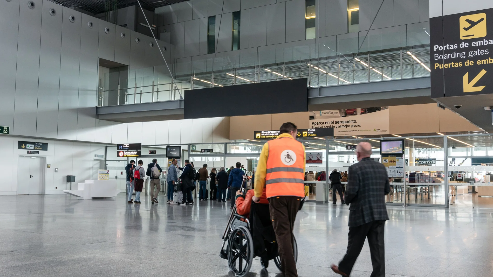 Una persona con discapacidad es ayudada a desplazarse en un aeropuerto en una silla de ruedas