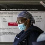 Una sanitaria pasa por un cartel en el que se informa de posibles efectos secundarios de la vacuna en Johannesburgo (Suráfrica)
