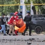 Policías y miembros del equipo de emergencias portan el cadáver de uno de los terroristas a las afueras de la iglesia en Makassar, Indonesia