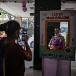 A woman poses for a photograph behind a cutout after receiving a COVID- 19 vaccine at a government hospital in Noida, a suburb of New Delhi, India, Wednesday, April 7, 2021. India hits another new peak with 115,736 coronavirus cases reported in the past 24 hours with New Delhi, Mumbai and dozens of other cities imposing night curfews to check the soaring infections. (AP Photo/Altaf Qadri)