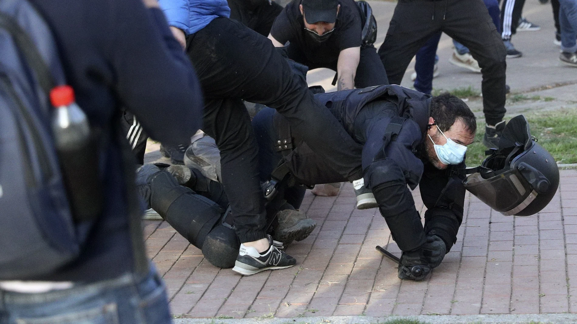 Radicales patean a un policía nacional en el suelo y sin casco