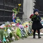 Una niña deja flores en la verga del Palacio de Buckhingham en recuerdo del príncipe Felipe