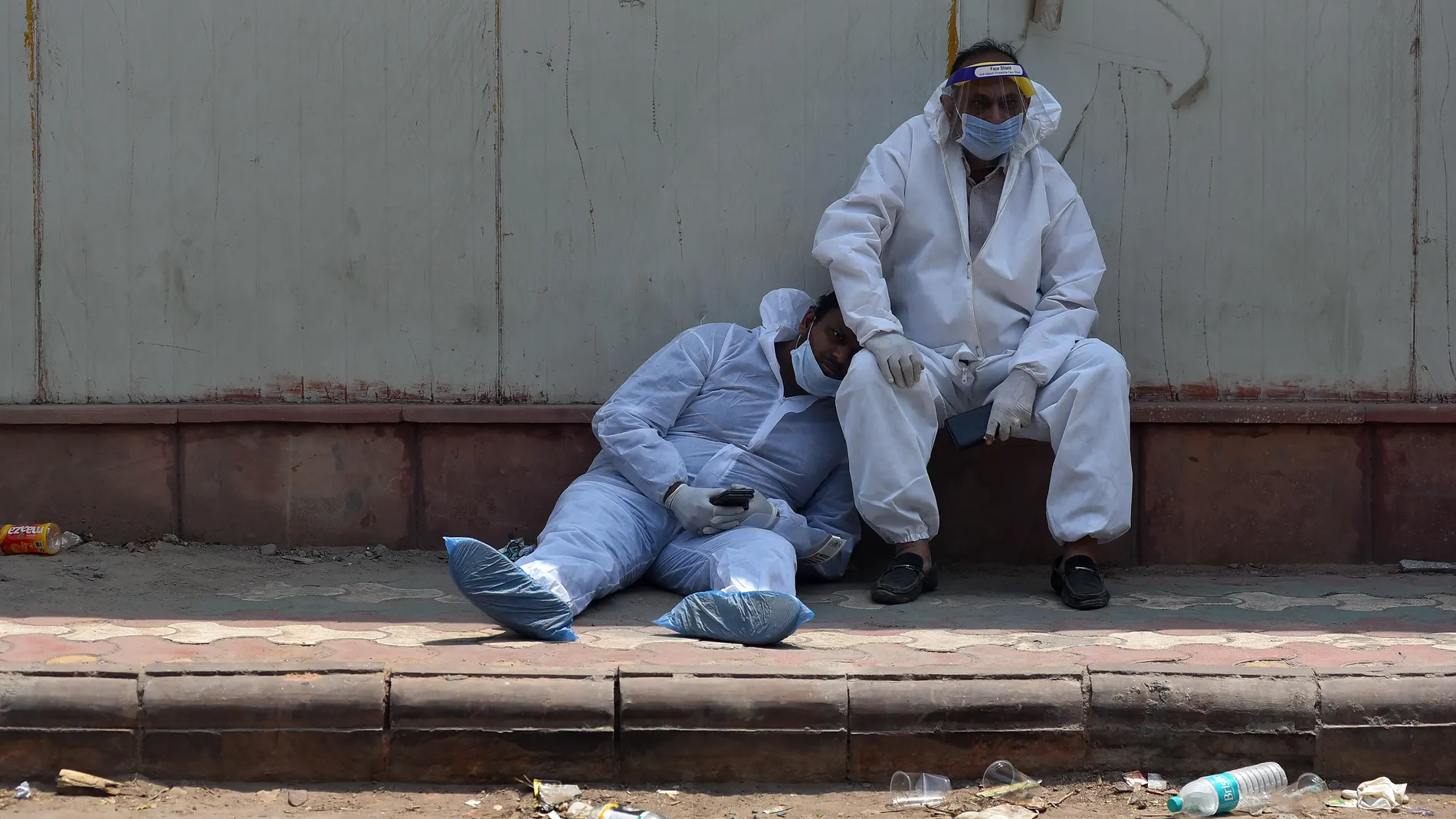 -FOTODELDIA- Nueva Delhi (India), 29/04/2021.- Dos paramédicos indios se toman un descanso a las puertas del depósito de cadáveres de un hospital en Nueva Delhi (India) este jueves. La India superó este jueves los 18 millones de casos tras batir un nuevo récord de infecciones, tras alcanzar casi los 380.000 contagios, además de contabilizar un nuevo máximo con más de 3.600 muertes en un día. EFE/IDREES MOHAMMED