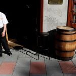 Un camarero espera la llegada de clientes a las puertas de un restaurante