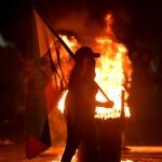 AME4898. CALI (COLOMBIA), 03/05/2021.- Una mujer camina con una bandera de Colombia durante una velatón en homenaje al joven Nicolás Guerrero, asesinado durante los enfrentamientos con miembros del Escuadrón Móvil Antidisturbios (ESMAD), hoy en Cali (Colombia). EFE/ Ernesto Guzmán Jr