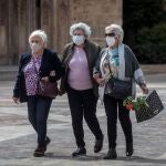 Tres señoras caminan cogidas del brazo en una céntrica plaza de Valencia