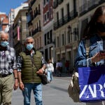 Varias personas pasean por las inmediaciones de la Puerta del Sol con mascarilla