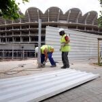 Unos operarios trabajan en la valla de las obras del Nuevo Mestalla, cuya construcción lleva más de doce años paradas
