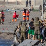 Miembros del ejército ayudando a varios inmigrantes a su llegada a la playa de El Tarajal, junto a la valla fronteriza , en Ceuta.