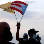 USA9824. SAN JUAN (PUERTO RICO), 18/05/2021.- Un hombre ondea hoy una bandera puertorriqueña mientras protesta en contra del contrato de LUMA Energy, empresa que asumirá parte de las funciones de la estatal Autoridad de la Energía Eléctrica (AEE), frente al Capitolio en San Juan, Puerto Rico (EE.UU). El gobernador de Puerto Rico, Pedro Pierluisi, presentó un presupuesto para el próximo año fiscal que supera en 233 millones de dólares al establecido por la entidad de control impuesta por Washington para supervisar al Ejecutivo local a causa de la deuda, por lo que habrá que esperar la respuesta de la entidad federal. EFE/Thais Llorca
