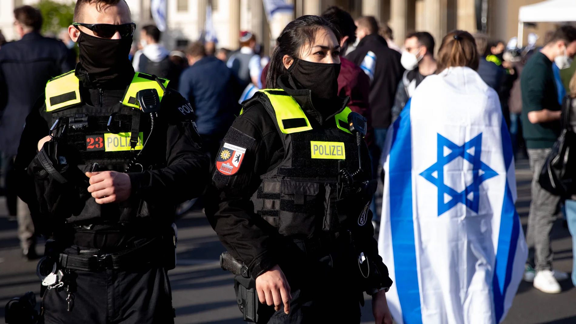 Una mujer con bandera de Israel junto a agentes de policía asiste a un mitin denominado 'Solidaridad con Israel y contra el antisemitismo' frente a la Puerta de Brandenburgo en Berlín, Alemania, el 20 de mayo