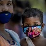 Una mujer sostiene a un niño mientras espera para realizar la prueba de Covid-19 en la aldea de Burha Mayong, distrito de Morigaon en Assam, India