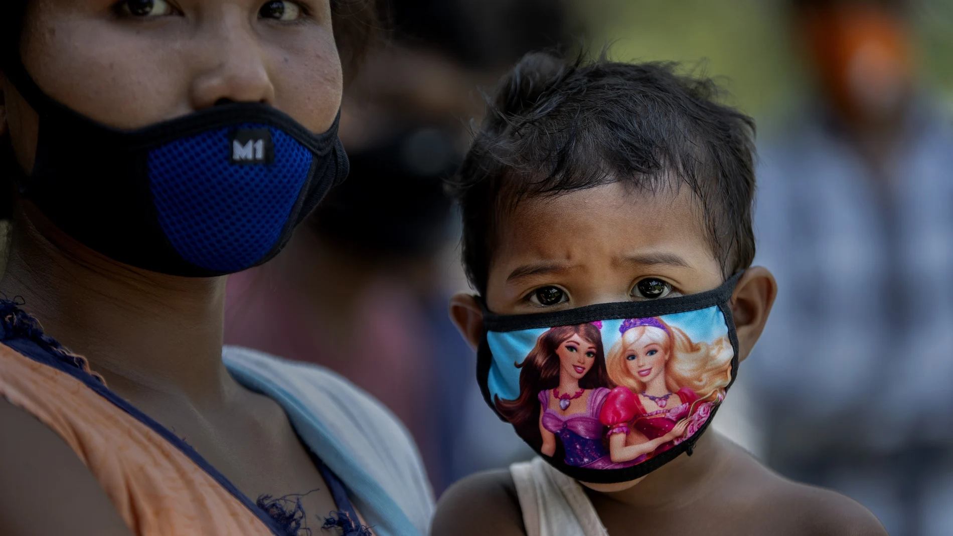Una mujer sostiene a un niño mientras espera para realizar la prueba de Covid-19 en la aldea de Burha Mayong, distrito de Morigaon en Assam, India