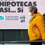 Imágenes de gente con mascarillas pasando por delante de bancos que anuncian hipotecas