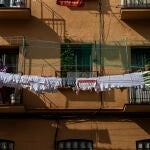 Imagen de una mujer tendiendo la ropa de la lavadora en el balcon de su casa en un edificio de Vallecas.