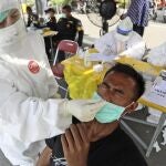 Un sanitario toma una muestra de hisopo nasal de un hombre durante una prueba de coronavirus obligatoria para quienes viajan entre la isla de Madura y la capital provincial de Surabaya (Indonesia)