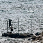 Personas (al fondo), instalan una valla en la playa del Tarajal, a 24 de junio de 2021, en Marruecos.