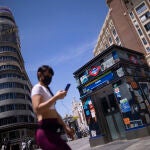 Una mujer camina con mascarilla en la Gran Vía