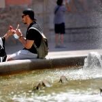 Dos personas se toman un helado junto a una fuente cuando este viernes la Agencia Estatal de Meteorología (Aemet) ha establecido la alerta nivel naranja por temperaturas que el sábado pueden alcanzar los 40 grados en el interior sur de la provincia de Valencia. EFE/Ana Escobar