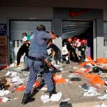 Durban (South Africa), 12/07/2021.- A member of the South African Police Forces tries to control looting during protests in Durban, South Africa, 12 July 2021. Former South Africa President Zuma was arrested on 07 July, and sentenced to 15 months in prison for contempt of court. Protests by his supporters included shops being looted, burned cars and the blocking of city streets in the country. (Protestas, Sudáfrica) EFE/EPA/STR