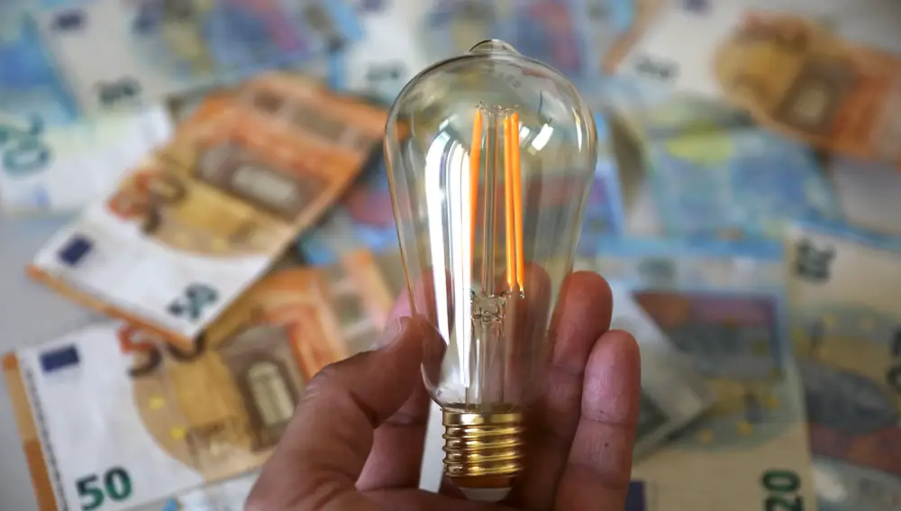 Bombilla encendida sobre dinero en efectivo