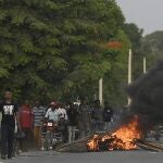 Men walk past a flaming barricade after violence broke out and hundreds of workers fled the area when demonstration near the home town of late President Jovenel Moise grew violent, ahead of his funeral in Quartier Morin, a districto of Cap Haitien, in northern Haiti, Wednesday, July 21, 2021. (AP Photo/Matias Delacroix)