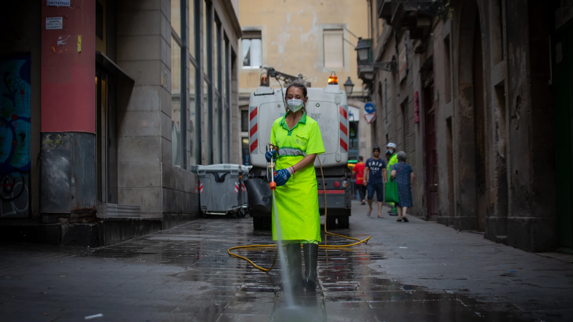 Una trabajadora limpia una vía de Barcelona