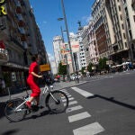Imagen de una chica de rojo en bicicleta por la Gran Vía.