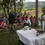 Friar Leopoldo Serrano celebrates an outdoor Mass at Mission San Francisco de Asis, in Honduras, Sunday, June 27, 2021. The pastor of souls has turned into a project manager and construction foreman for the families of La Reina, a nearby Honduran village buried in an epic mudslide in November 2020, its families among nearly half a million Central Americans displaced by Hurricanes Eta and Iota. (AP Photo/Rodrigo Abd)