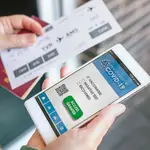 Una mujer sostiene su teléfono con el certificado del pasaporte covid y la tarjeta de embarque