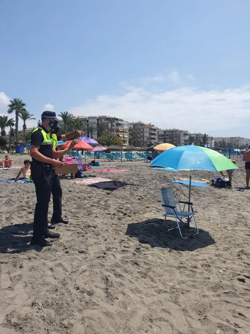 Dos policías locales vigilan una sombrilla vacía en la playa de Torrox