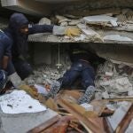 Un equipo de bomberos busca supervivientes bajo los escombros de un edificio