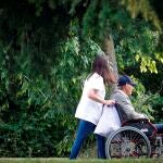 Una mujer pasea con un hombre en silla de ruedas
