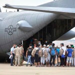 Un grupo de jóvenes y familias afganas, se dirigen a subir a un avión estadounidense para ser trasladados a Alemania