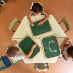 Varios niños de infantil dibujan en una pizarra.