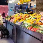 Imagen de una mujer mayor frente a una frutería.