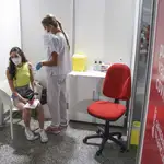 Una sanitaria vacuna a una adolescente con la primera dosis de la vacuna Moderna en la Ciudad de las Artes