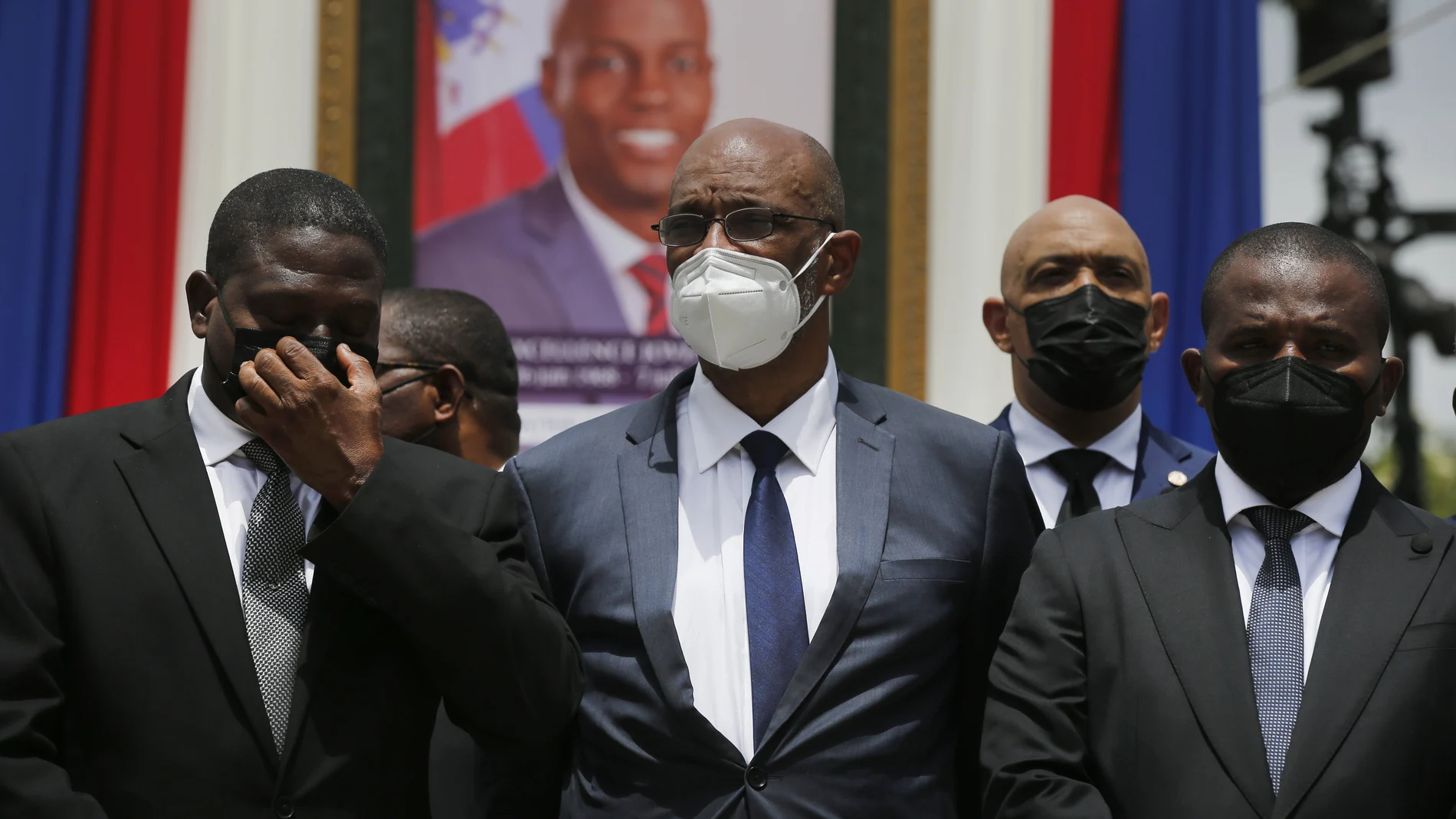 FILE - In this July 20, 2021 file photo, Haiti's designated Prime Minister Ariel Henry, center, and interim Prime Minister Claude Joseph, right, pose for a group photo with other authorities in front of a portrait of slain Haitian President Jovenel Moise at the National Pantheon Museum during a memorial service for Moise in Port-au-Prince, Haiti. Haiti’s chief prosecutor has asked a judge to charge Henry in the slaying of his predecessor and barred him from leaving the country. (AP Photo/Joseph Odelyn, File)
