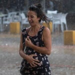Una mujer corre bajo la lluvia en Sevilla