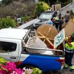 Varias personas de mantenimiento del Ayuntamiento y bomberos colaboran en recoger las pertenencias de los vecinos del núcleo urbano de Todoque durante el desalojo de sus viviendas